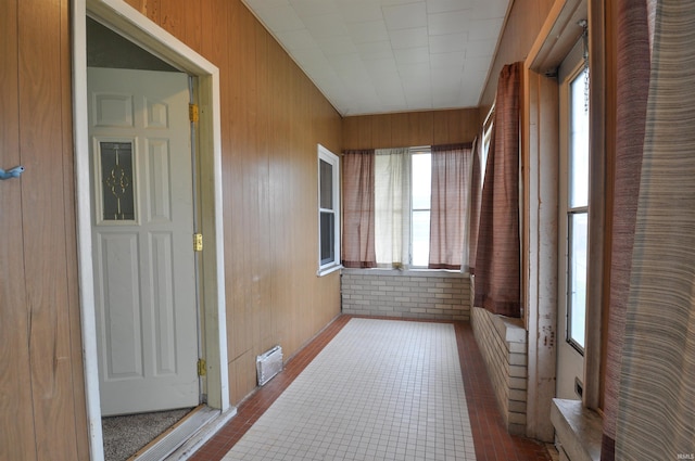 corridor with wood walls, plenty of natural light, and tile floors