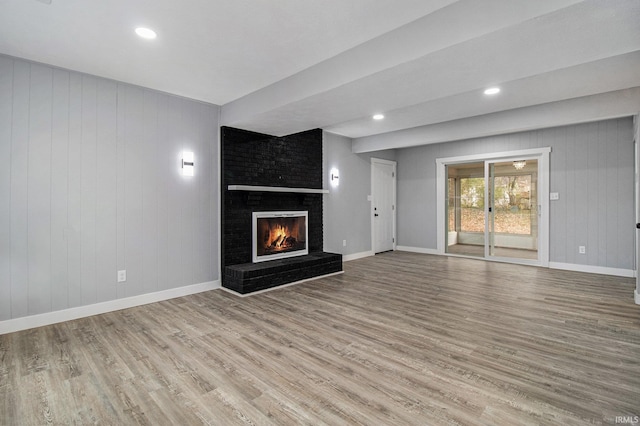 unfurnished living room with a brick fireplace and light hardwood / wood-style flooring