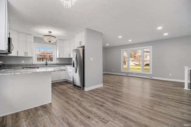 kitchen with light stone countertops, white cabinetry, appliances with stainless steel finishes, and an inviting chandelier