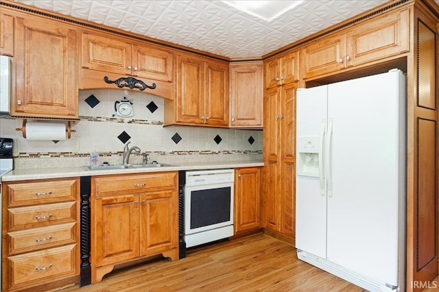 kitchen with white appliances, light hardwood / wood-style floors, tasteful backsplash, and sink