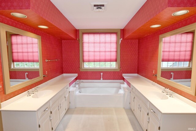 bathroom with a wealth of natural light, a bathtub, and double sink vanity