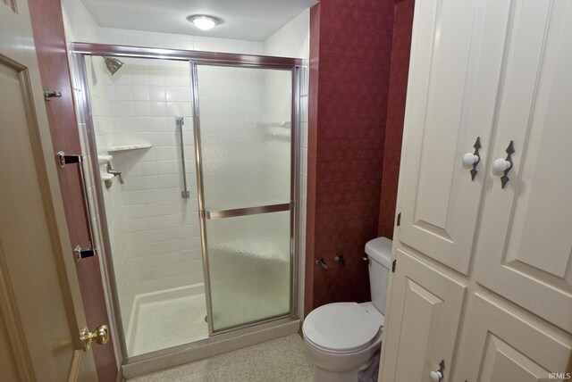 bathroom featuring toilet and a shower with shower door