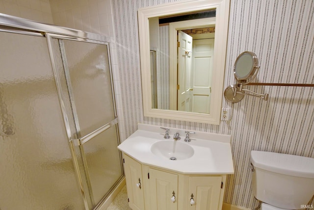 bathroom featuring a shower with shower door, vanity, and toilet