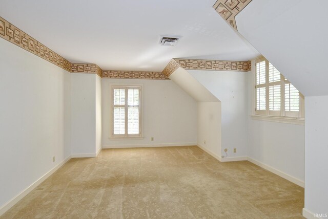 bonus room with light colored carpet and lofted ceiling