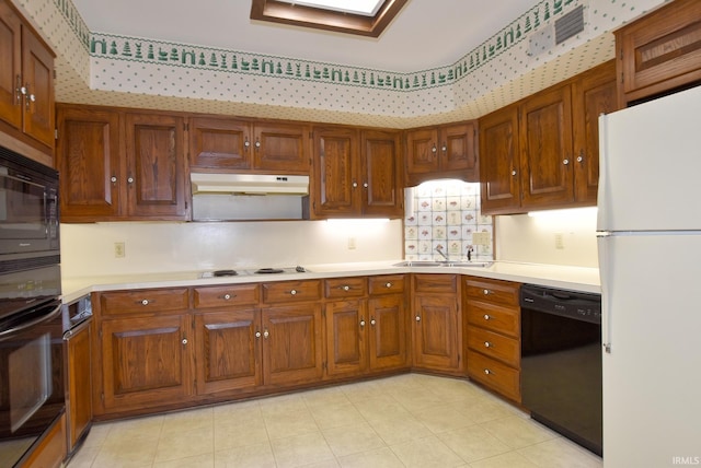 kitchen with sink, light tile patterned flooring, a skylight, and black appliances