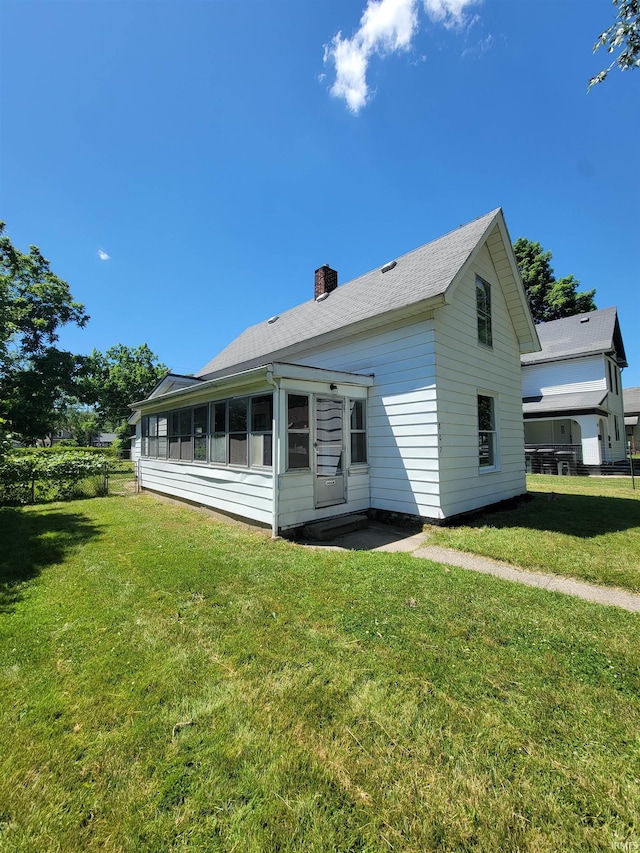 back of property with a lawn and a sunroom