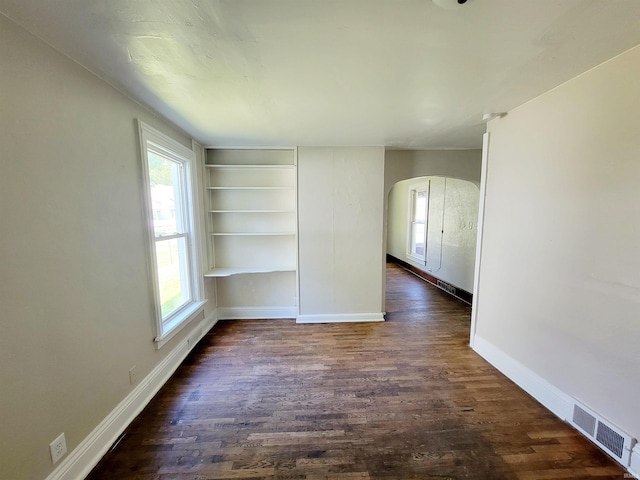 spare room with built in features and dark hardwood / wood-style floors