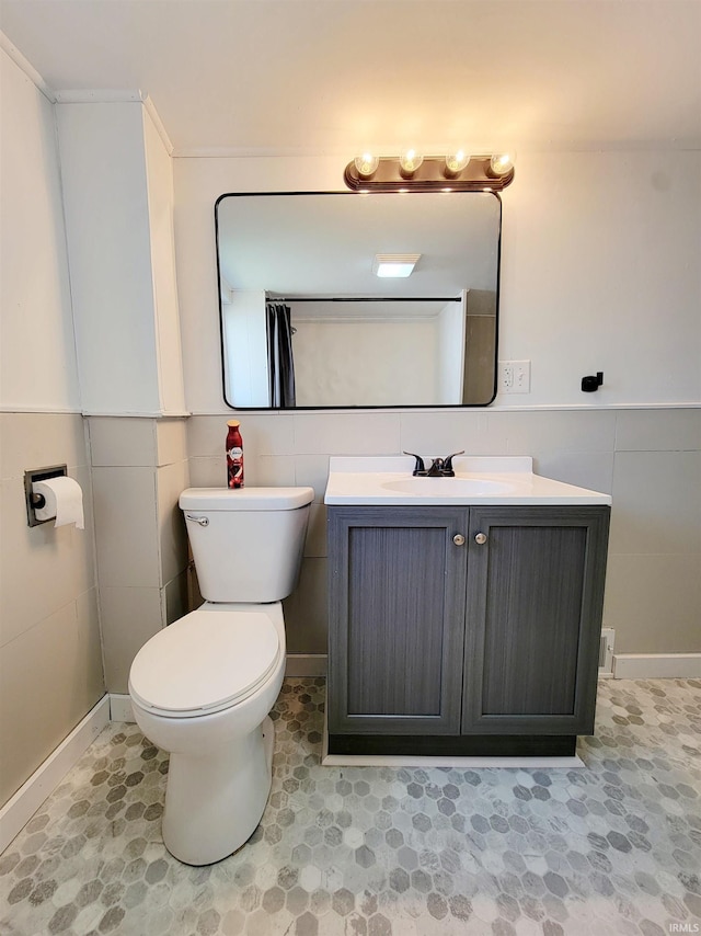 bathroom with vanity, toilet, and tile walls