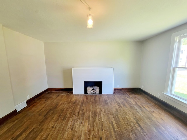 unfurnished living room featuring dark hardwood / wood-style floors and a healthy amount of sunlight