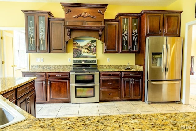 kitchen featuring light stone countertops, sink, light tile patterned flooring, and stainless steel appliances