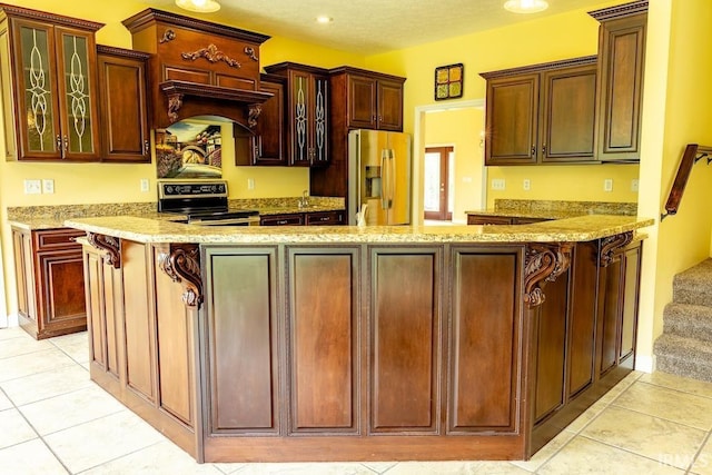 kitchen with stainless steel fridge with ice dispenser, stove, light tile patterned floors, and custom range hood