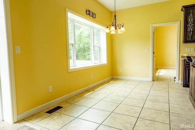 unfurnished dining area featuring light tile patterned floors and an inviting chandelier