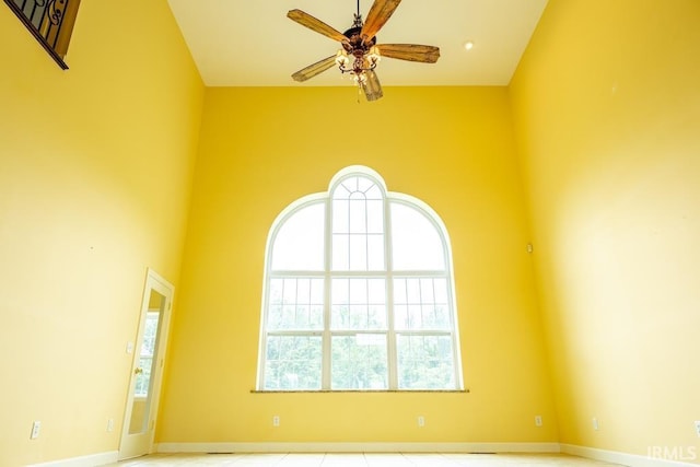 spare room featuring ceiling fan and a towering ceiling