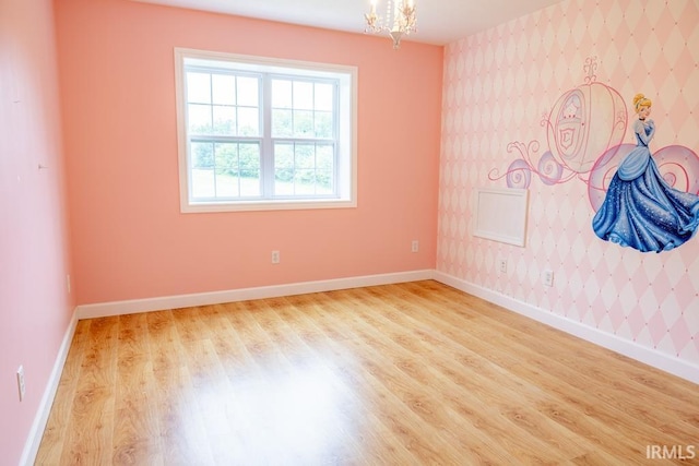 spare room with light wood-type flooring and a chandelier