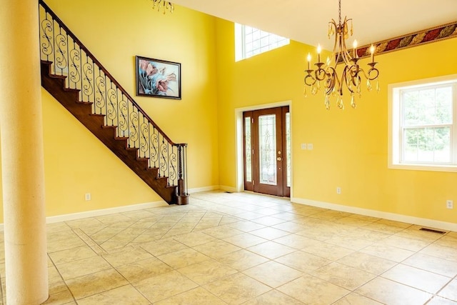 tiled entrance foyer with a high ceiling, a wealth of natural light, and a chandelier