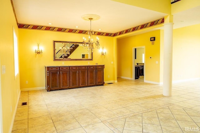 tiled empty room featuring an inviting chandelier and decorative columns