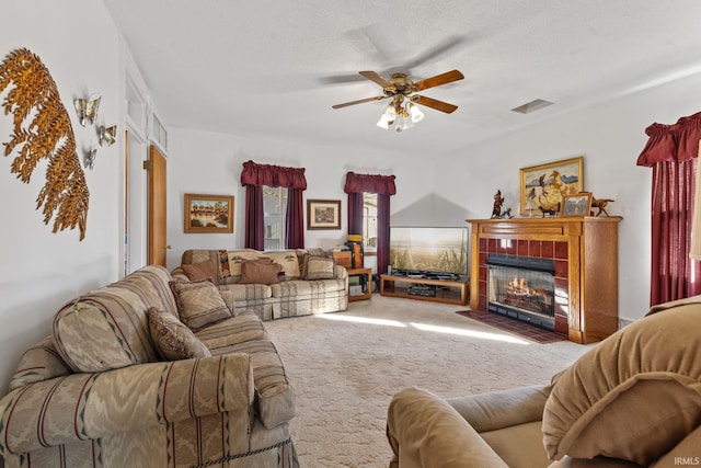 carpeted living room with a tile fireplace, a textured ceiling, and ceiling fan