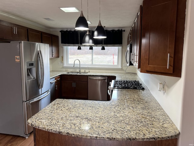 kitchen featuring light stone countertops, appliances with stainless steel finishes, ornamental molding, sink, and decorative light fixtures