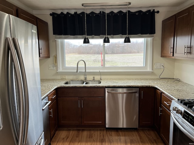 kitchen featuring sink, light stone countertops, appliances with stainless steel finishes, decorative light fixtures, and dark hardwood / wood-style flooring