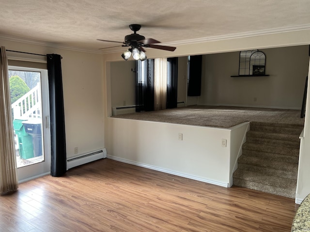 spare room featuring ceiling fan, light hardwood / wood-style floors, a textured ceiling, and a baseboard heating unit