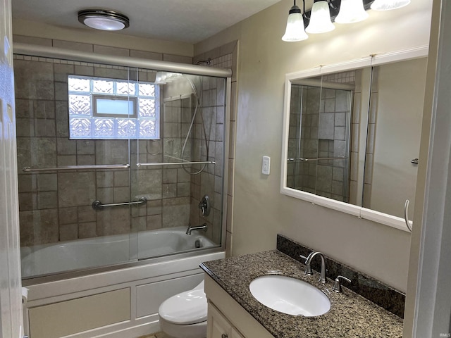 full bathroom featuring vanity, bath / shower combo with glass door, and toilet