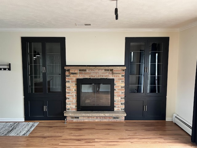 unfurnished living room with ornamental molding, a textured ceiling, hardwood / wood-style flooring, a baseboard radiator, and a fireplace