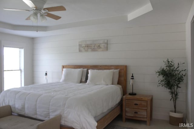 bedroom with a raised ceiling and ceiling fan