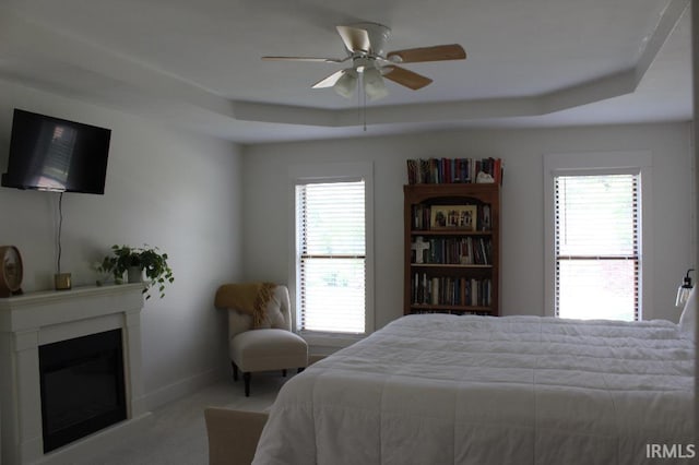 bedroom with a tray ceiling, ceiling fan, and light colored carpet