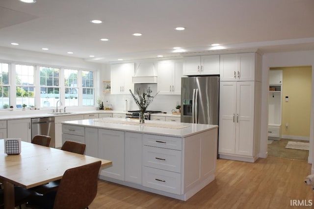 kitchen with white cabinetry, sink, custom range hood, and appliances with stainless steel finishes