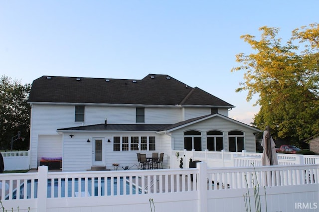 back of property with a fenced in pool