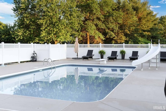 view of pool with a patio, a water slide, fence, a diving board, and a fenced in pool