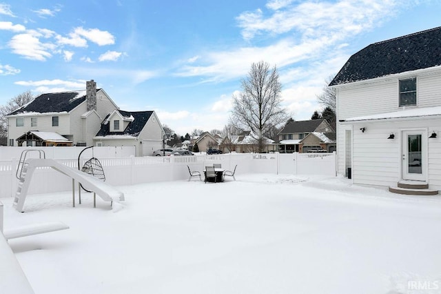 yard covered in snow with entry steps, fence, and a residential view