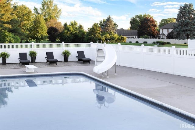 view of swimming pool featuring a fenced in pool, fence, a water slide, and a patio