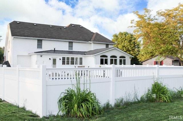 rear view of house with a standing seam roof, a fenced backyard, and metal roof