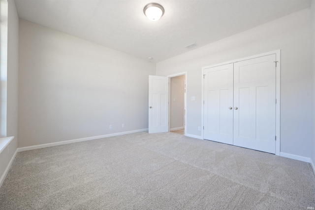 unfurnished bedroom featuring light carpet and a closet