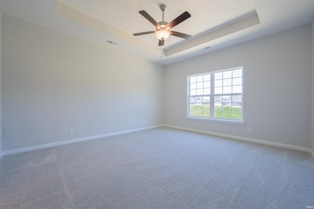 spare room with carpet flooring, a raised ceiling, and ceiling fan