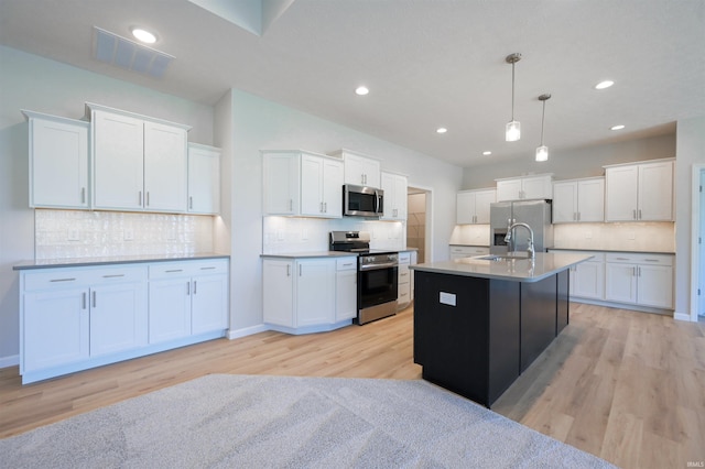 kitchen featuring white cabinets, appliances with stainless steel finishes, and hanging light fixtures