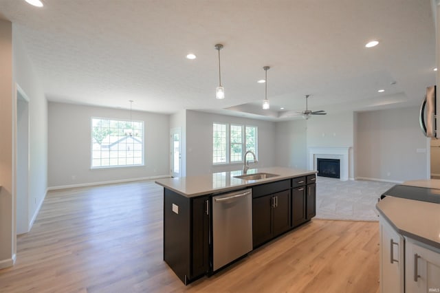 kitchen with decorative light fixtures, sink, stainless steel dishwasher, and a center island with sink