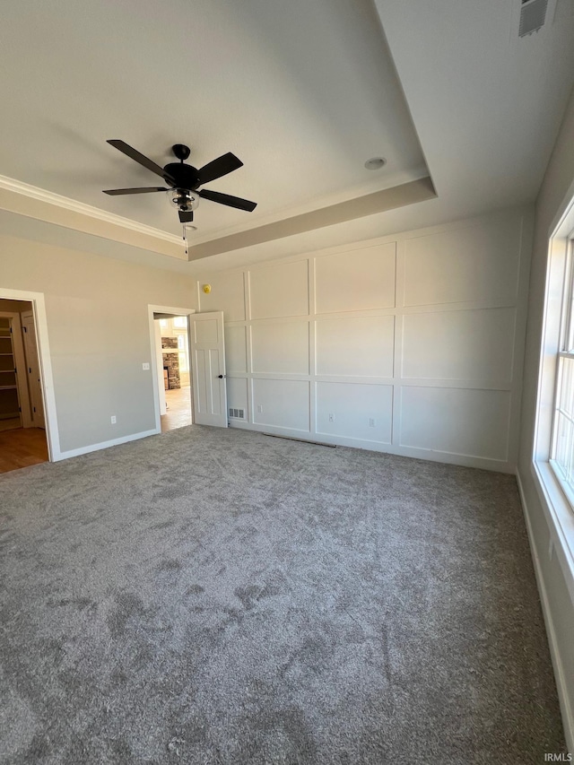 unfurnished bedroom with carpet floors, a tray ceiling, and ceiling fan