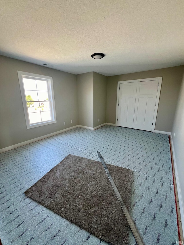 unfurnished bedroom featuring a textured ceiling and light carpet