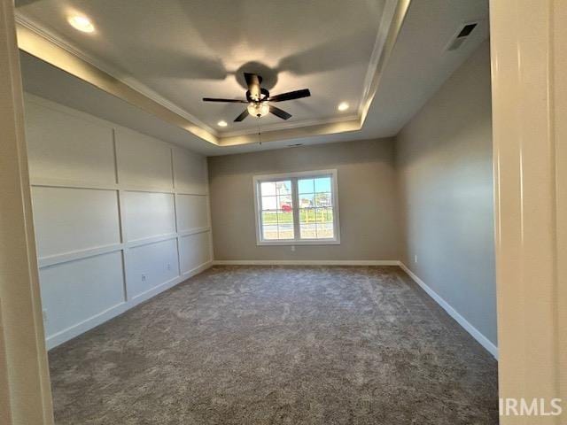 carpeted empty room featuring a tray ceiling, ceiling fan, and ornamental molding