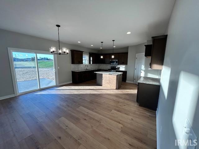 kitchen with tasteful backsplash, light wood-type flooring, decorative light fixtures, and a notable chandelier