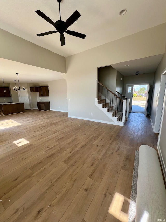 unfurnished living room with wood-type flooring and ceiling fan with notable chandelier