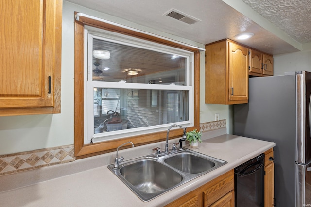 kitchen featuring black dishwasher, sink, stainless steel fridge, and a textured ceiling