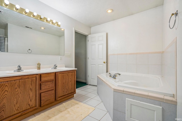 bathroom with vanity, tiled tub, tile patterned floors, and a textured ceiling