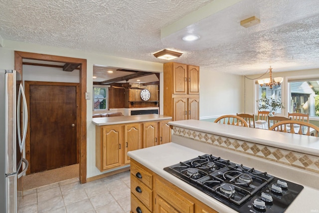 kitchen featuring a textured ceiling, stainless steel fridge, black gas cooktop, and a chandelier