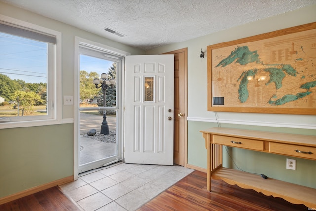 entryway with built in desk, a textured ceiling, and light hardwood / wood-style floors