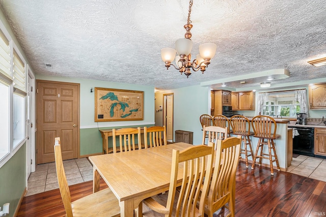 dining area with a textured ceiling, light hardwood / wood-style flooring, and a chandelier