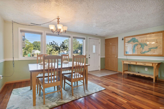 dining room with a textured ceiling, a notable chandelier, and dark hardwood / wood-style flooring