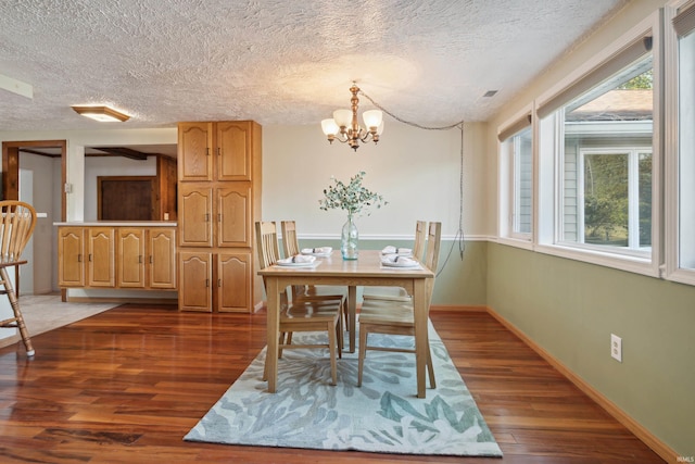 dining room with dark wood-type flooring, a textured ceiling, and an inviting chandelier